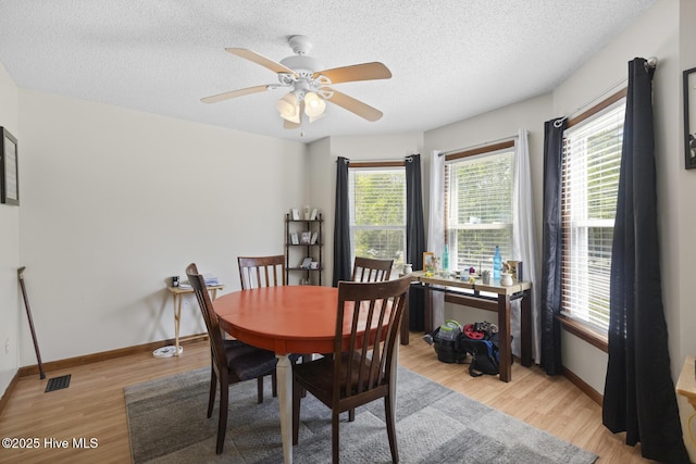 dining area featuring baseboards, a textured ceiling, visible vents, and light wood-type flooring