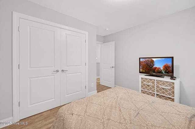 unfurnished bedroom featuring a closet, baseboards, and light wood-type flooring
