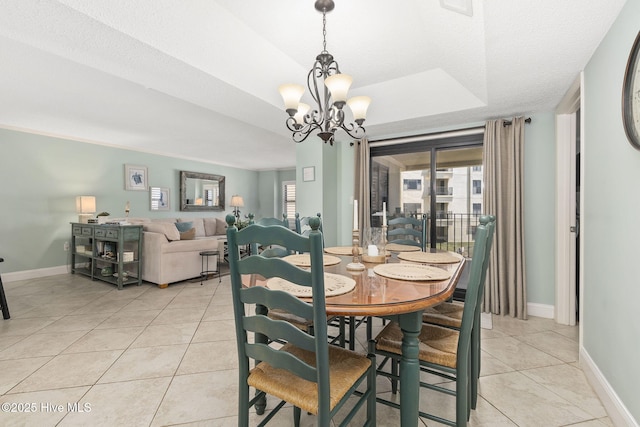 dining space with a tray ceiling, a chandelier, baseboards, and light tile patterned floors