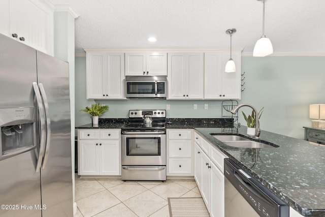 kitchen with a sink, dark stone counters, decorative light fixtures, appliances with stainless steel finishes, and light tile patterned flooring