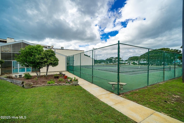view of tennis court featuring fence and a lawn