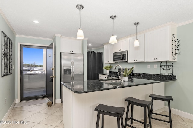 kitchen featuring baseboards, light tile patterned floors, ornamental molding, a peninsula, and appliances with stainless steel finishes