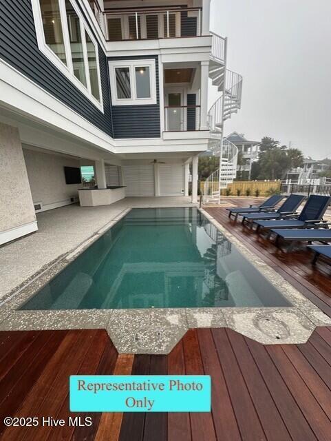 view of swimming pool featuring a fenced in pool, a patio area, a wooden deck, and stairway