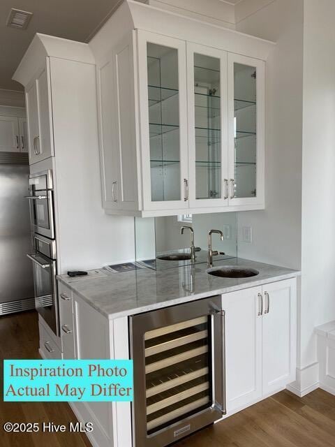 bar featuring stainless steel appliances, wet bar, wine cooler, visible vents, and dark wood-style floors