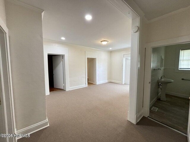 hallway with a sink, baseboards, recessed lighting, ornamental molding, and carpet