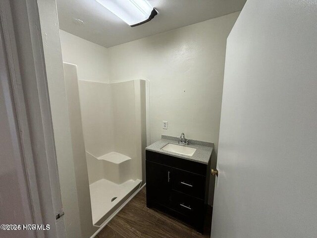 bathroom featuring wood finished floors, a stall shower, and vanity