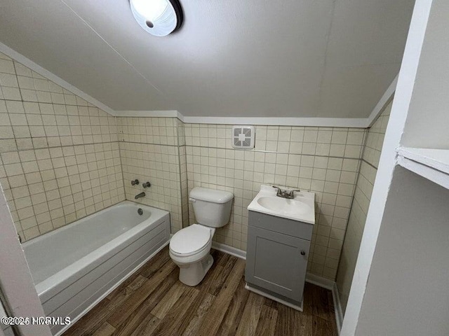 full bath featuring a bathing tub, vanity, wood finished floors, toilet, and lofted ceiling