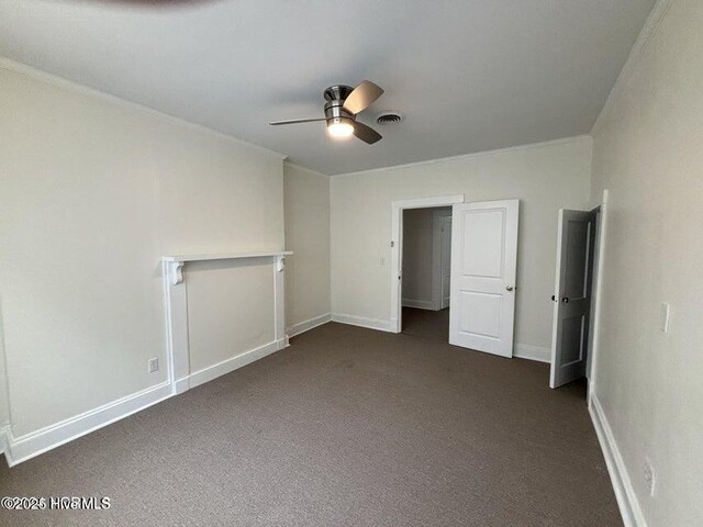unfurnished bedroom featuring dark colored carpet, ceiling fan, baseboards, visible vents, and crown molding