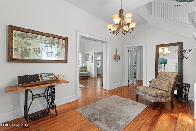 living area with baseboards, a chandelier, and hardwood / wood-style floors