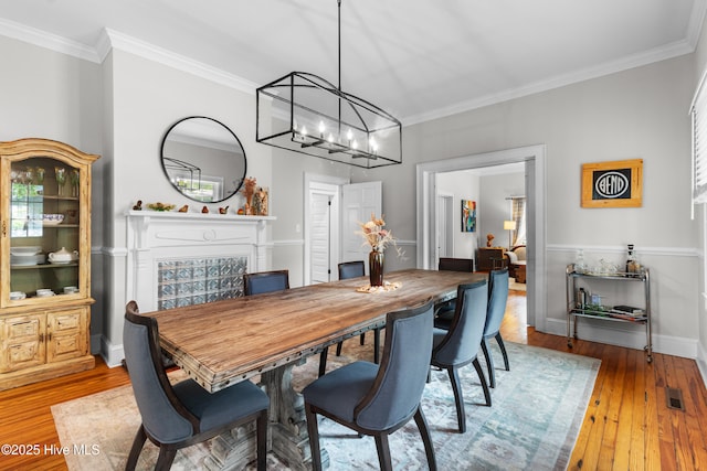dining area with light wood-type flooring, ornamental molding, baseboards, and a chandelier