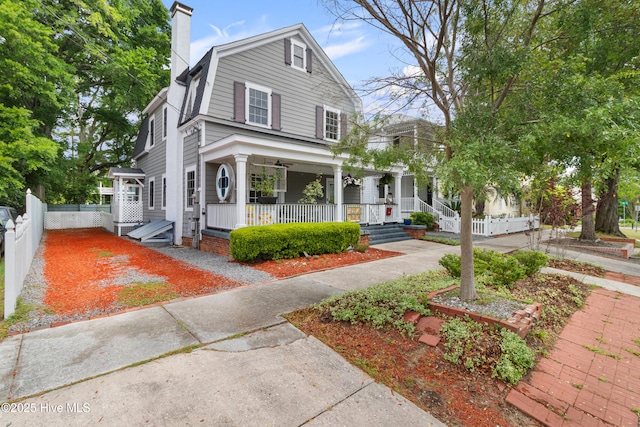 view of front of house with covered porch, fence, and a chimney