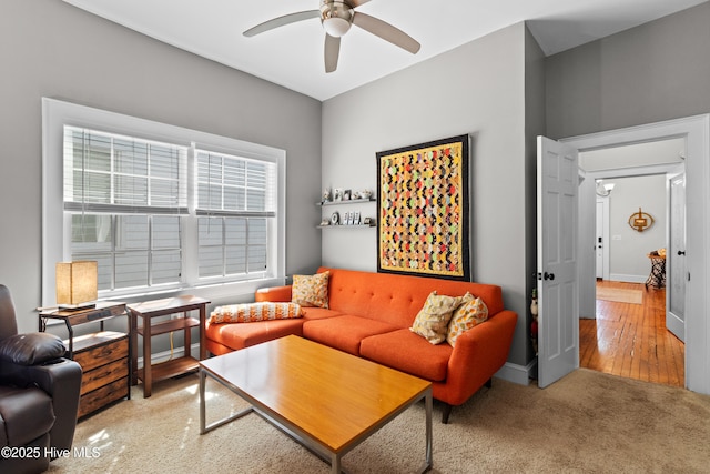 living area with baseboards, a ceiling fan, and carpet flooring