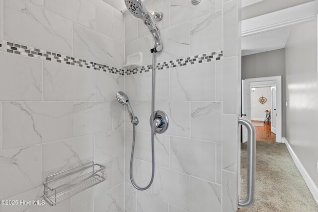 full bath with baseboards and tiled shower