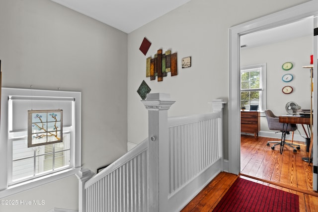 corridor with an upstairs landing and hardwood / wood-style floors