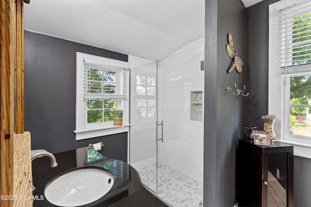 bathroom with a sink, a shower stall, and lofted ceiling