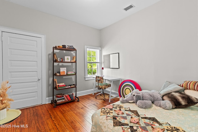 bedroom with baseboards, visible vents, and hardwood / wood-style flooring