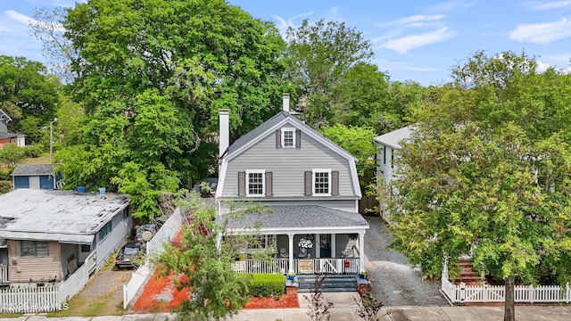 rear view of house featuring fence, a chimney, and a porch