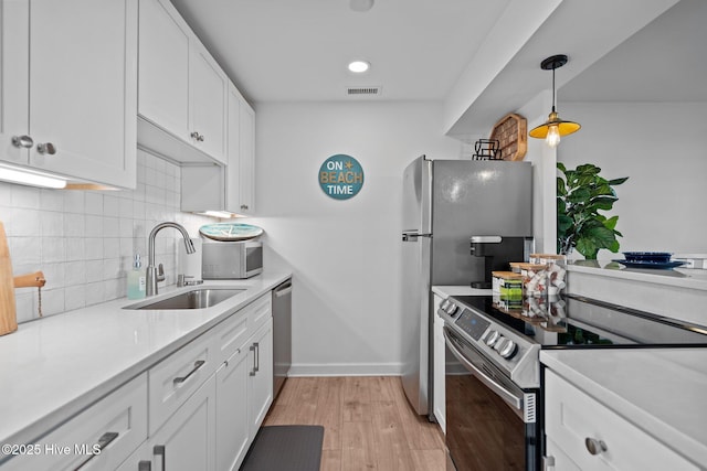 kitchen with visible vents, a sink, stainless steel appliances, white cabinets, and light wood-type flooring