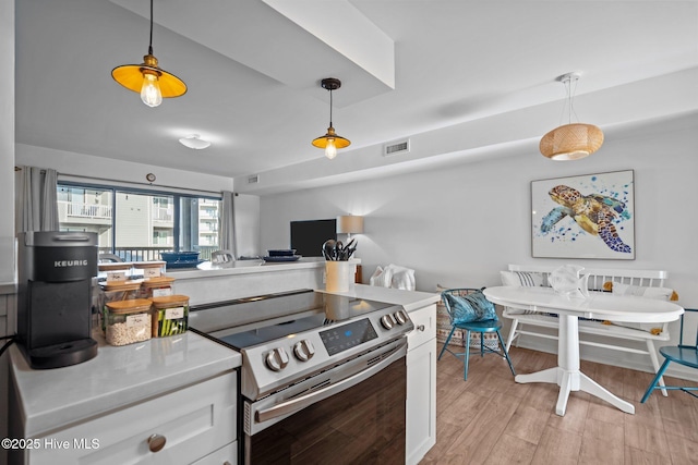 kitchen with hanging light fixtures, light wood-type flooring, and stainless steel range with electric cooktop