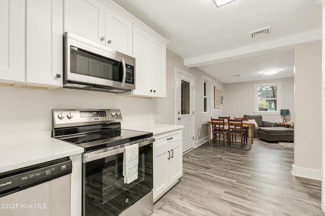 kitchen featuring appliances with stainless steel finishes, light wood finished floors, visible vents, and light countertops