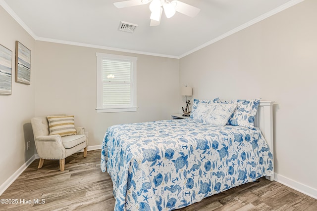 bedroom featuring wood finished floors, visible vents, crown molding, baseboards, and ceiling fan