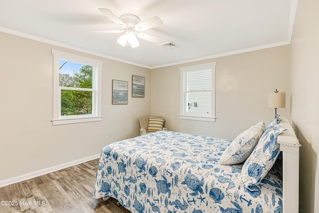 bedroom with baseboards, crown molding, wood finished floors, and visible vents