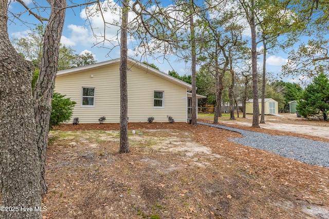 view of side of home with an outdoor structure and a storage shed