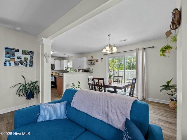 living room with baseboards, wood finished floors, a notable chandelier, and visible vents