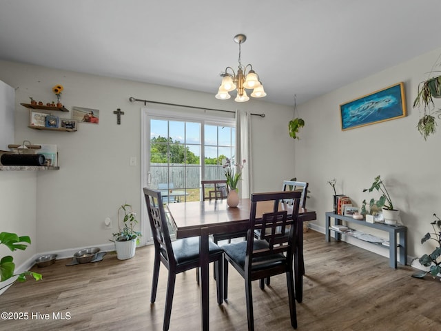 dining space featuring baseboards, wood finished floors, and a chandelier