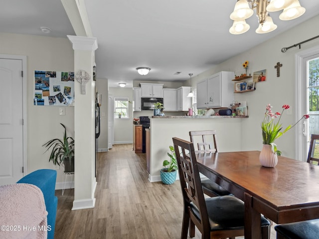 dining room with decorative columns, baseboards, a notable chandelier, and light wood-style flooring