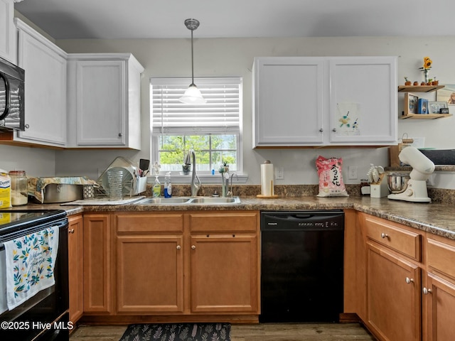 kitchen featuring wood finished floors, white cabinetry, a sink, black appliances, and decorative light fixtures