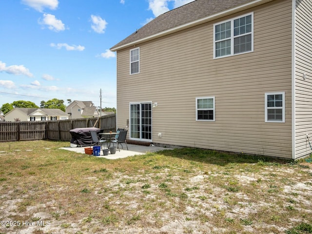 rear view of property with fence, a yard, and a patio area