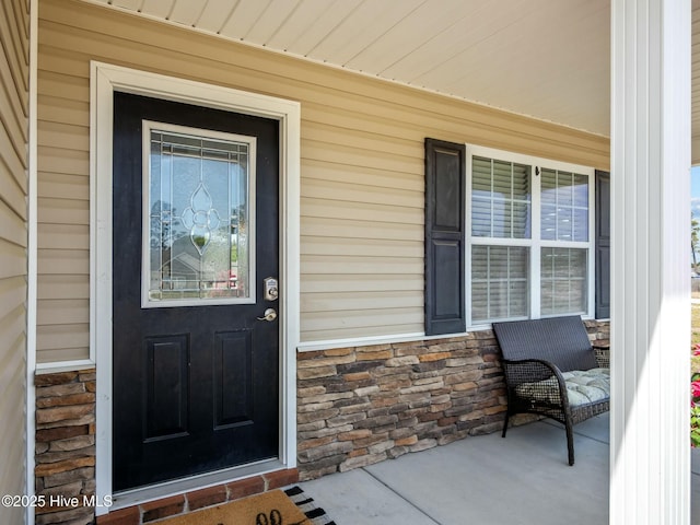 property entrance featuring covered porch and stone siding