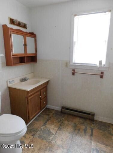 bathroom with tile walls, toilet, wainscoting, vanity, and a baseboard heating unit