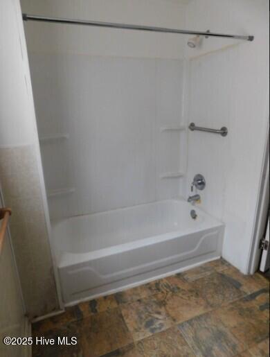 bathroom with stone finish floor and shower / bathing tub combination