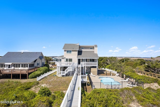 601 Caswell Beach Rd, Caswell Beach, NC 28465 - back of house featuring a chimney, a fenced in pool, stairs, a fenced backyard, and roof with shingles