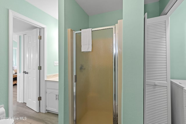 601 Caswell Beach Rd, Caswell Beach, NC 28465 - bathroom featuring wood finished floors, connected bathroom, a closet, a stall shower, and washer / clothes dryer