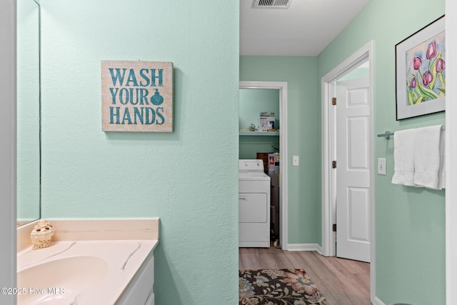 601 Caswell Beach Rd, Caswell Beach, NC 28465 - bathroom featuring wood finished floors, separate washer and dryer, vanity, a textured wall, and visible vents