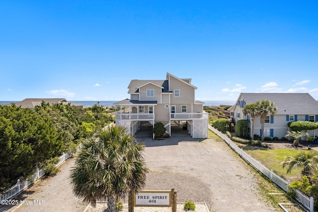 601 Caswell Beach Rd, Caswell Beach, NC 28465 - view of front of house featuring a carport, a water view, dirt driveway, fence, and stairs