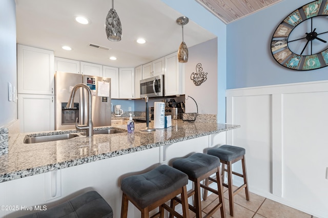 kitchen featuring a peninsula, light stone countertops, visible vents, and appliances with stainless steel finishes
