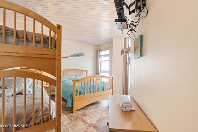 bedroom with wood ceiling and stone tile flooring