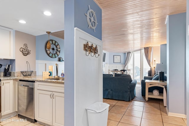 kitchen featuring stainless steel dishwasher, light stone counters, light tile patterned floors, and white cabinets