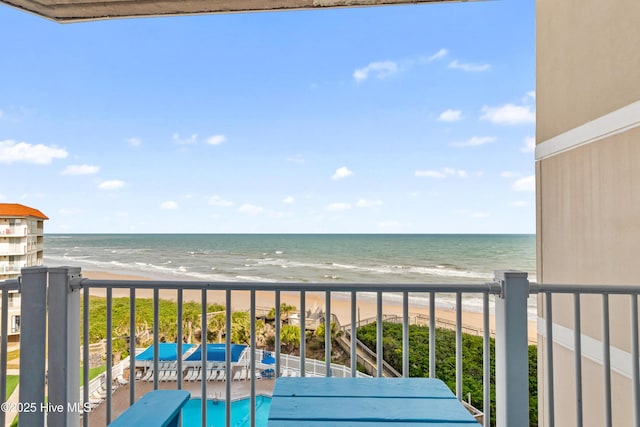 balcony with a water view and a view of the beach