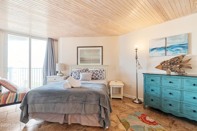 bedroom featuring baseboards, stone finish floor, wood ceiling, and access to exterior