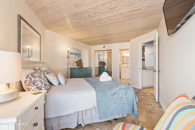 bedroom with baseboards, ensuite bathroom, wooden ceiling, and stone tile flooring