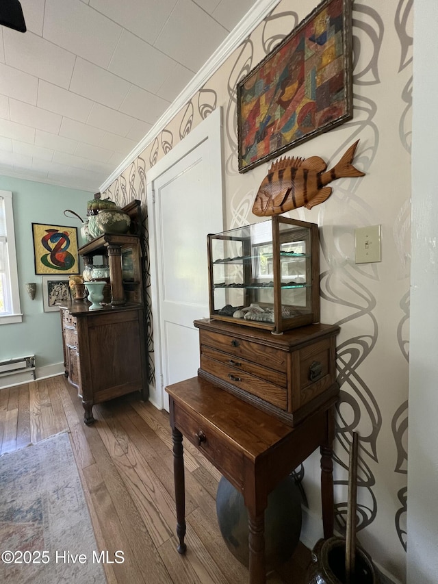 interior space featuring baseboard heating, ornamental molding, and wood finished floors