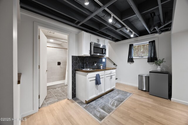 40 Inverness Rd, Pinehurst, NC 28374 - kitchen featuring stainless steel microwave, white cabinetry, dark countertops, and light wood-style flooring