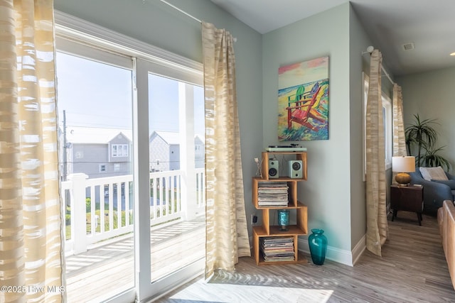 doorway to outside featuring baseboards, wood finished floors, and a wealth of natural light