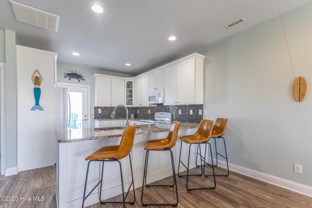 kitchen with white appliances, visible vents, stone counters, and a sink