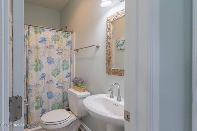 bathroom featuring toilet, a shower with curtain, and a sink